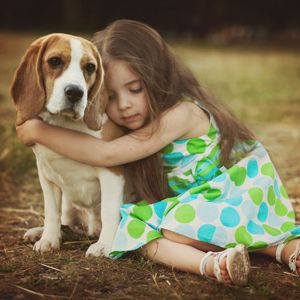 little girl is holding dog outdoors